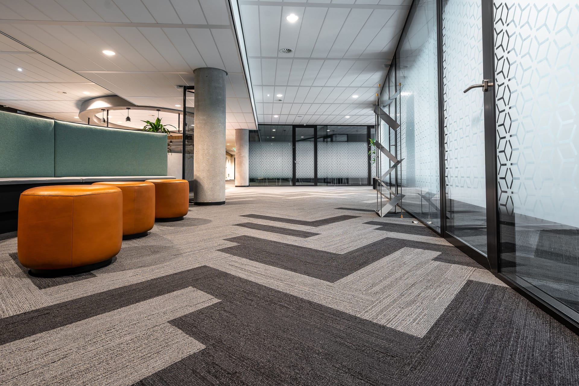 A bright modern office lobby with a clean carpet-tile floor and seating