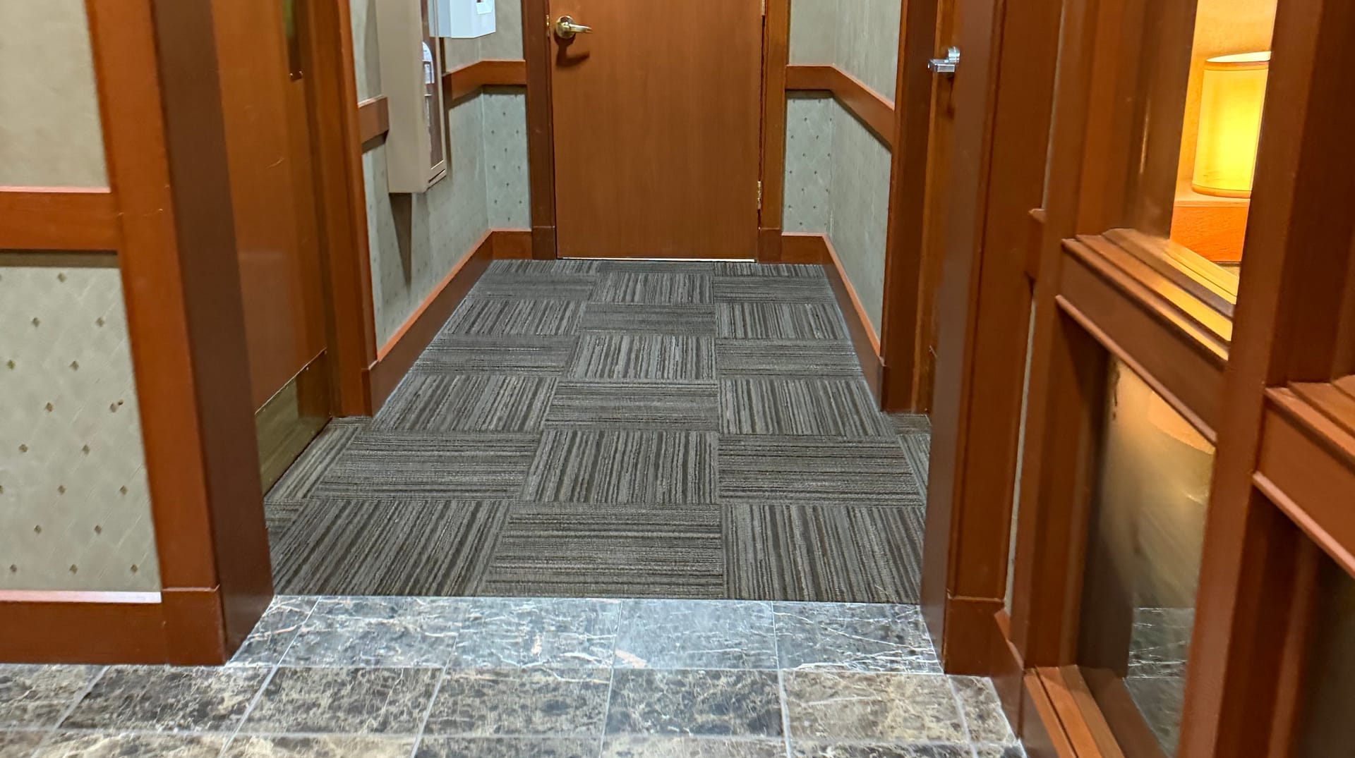 A cleaned office corridor running from polished stone tile onto carpet tile