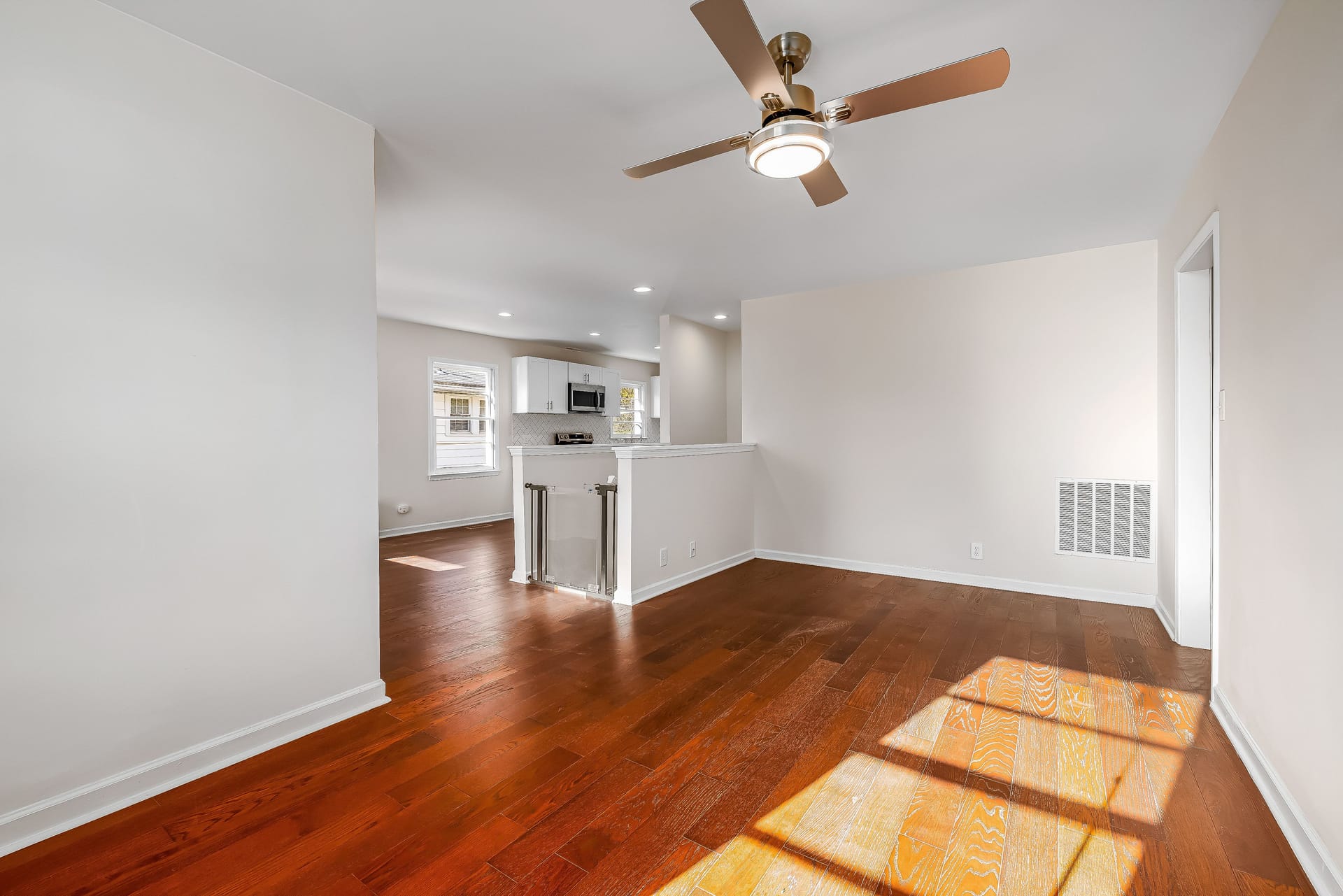 An empty apartment living room with sunlight across freshly cleaned hardwood